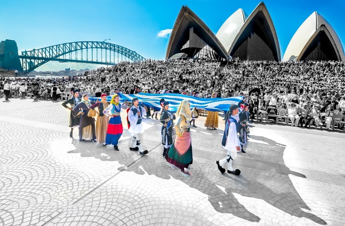 Hellenic Lyceum dancers in traditional costume carrying the Greek flag at the Sydney Opera House
